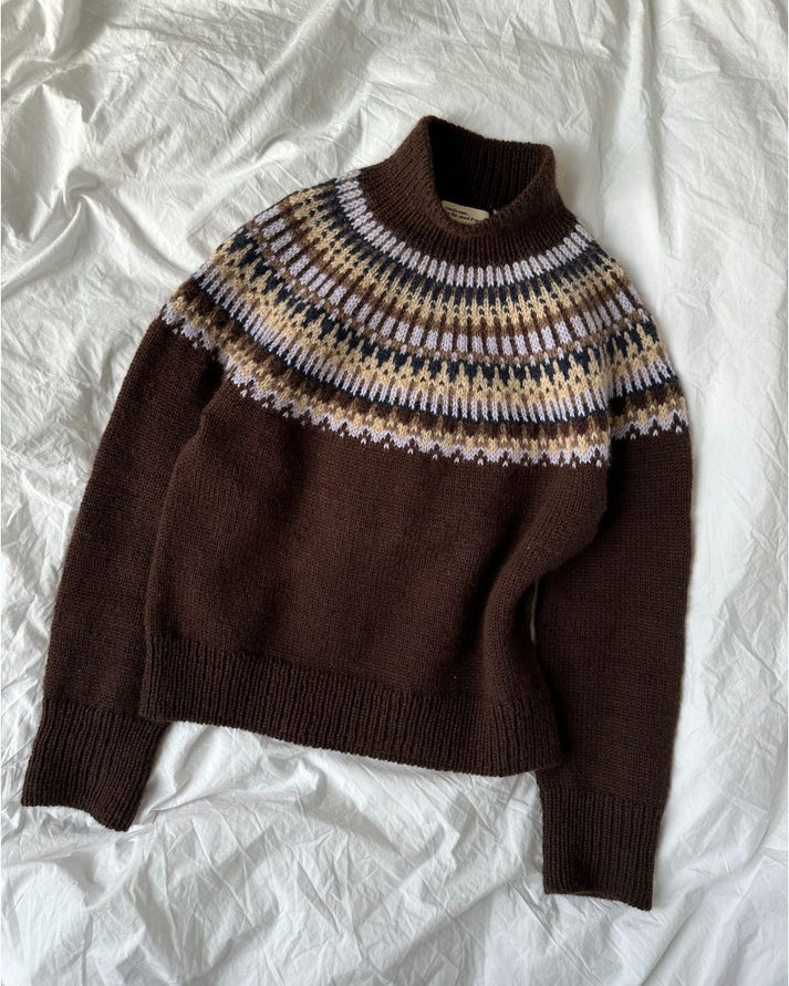 Celeste Sweater on näyttävä, moderni ja taidokkaasti suunniteltu kirjoneulevillapaita, jota koristaa upea pyöreä kaarroke.