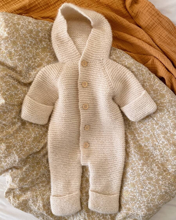 Selma’s Sleep Suit on suloinen, muhkea ja ihanan lämmin hupullinen vauvojen ja taaperoiden neulehaalari.
