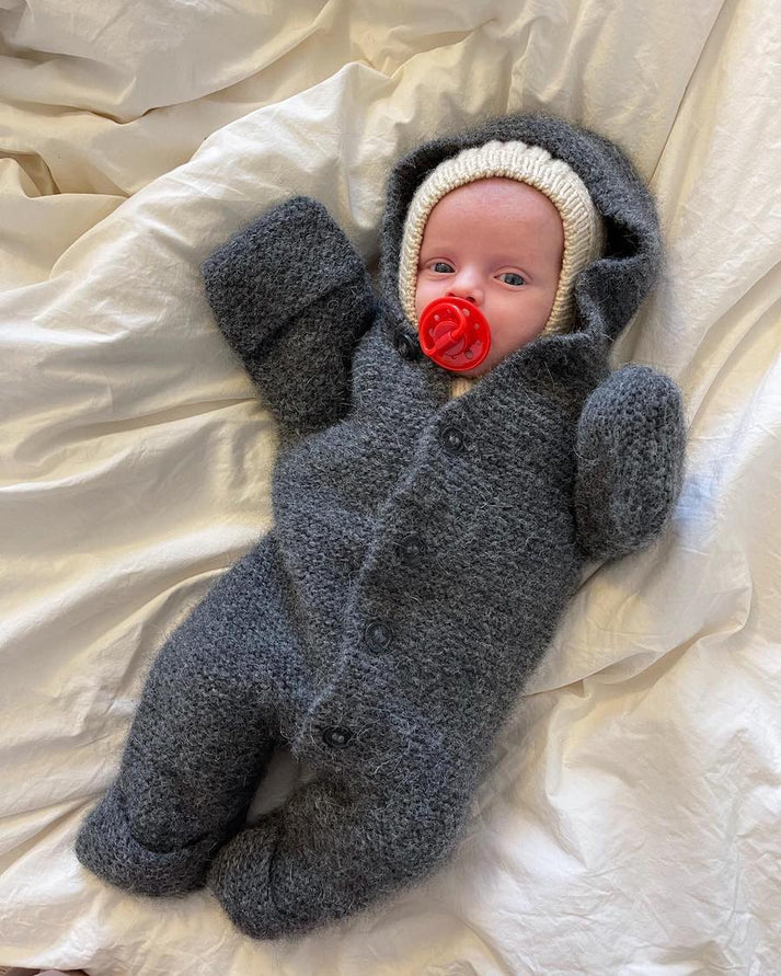 Selma’s Sleep Suit on suloinen, muhkea ja ihanan lämmin hupullinen vauvojen ja taaperoiden neulehaalari.